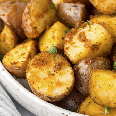 Close up of roasted potatoes in a white bowl.