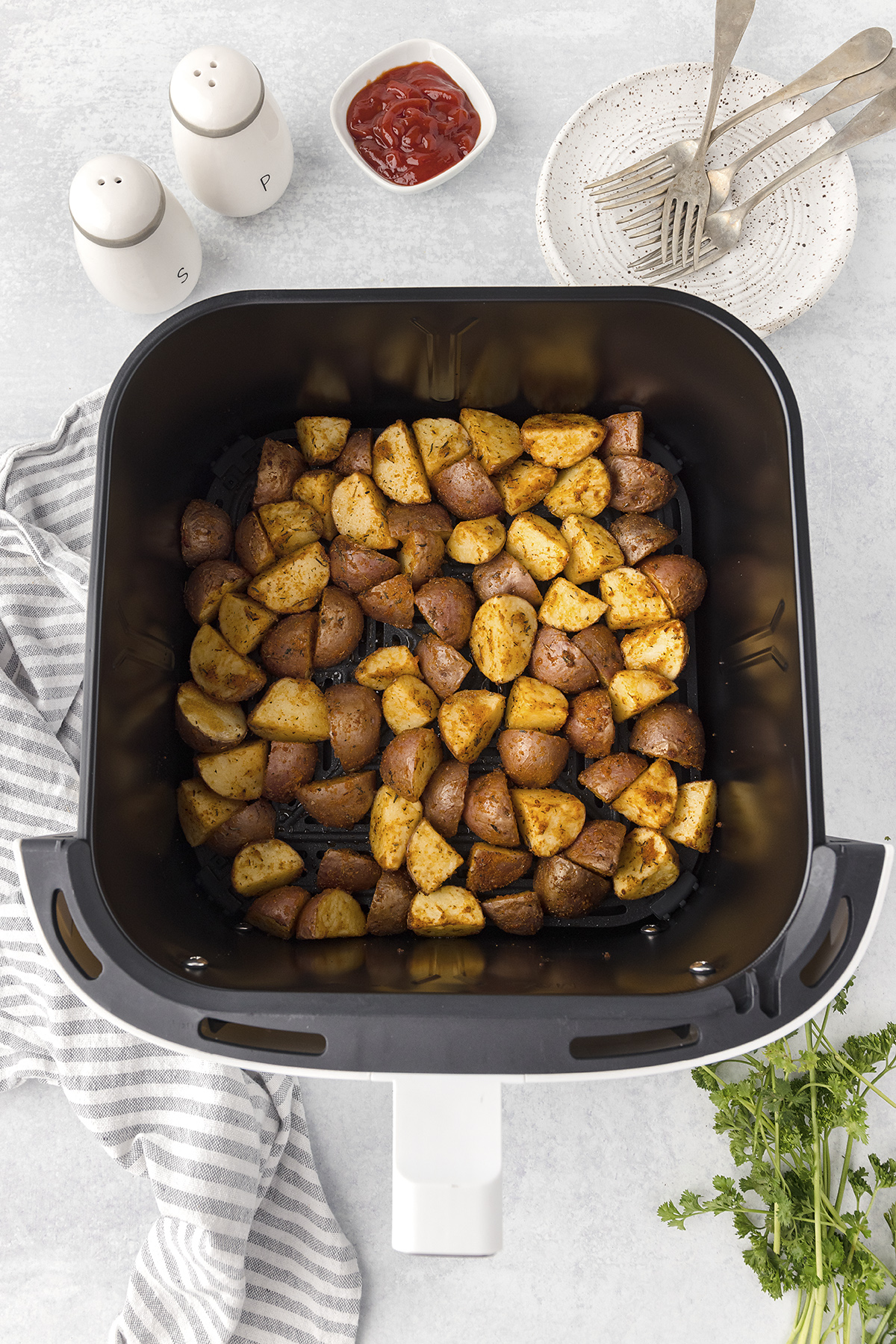 Cooked roasted red potatoes in an air fryer basket.