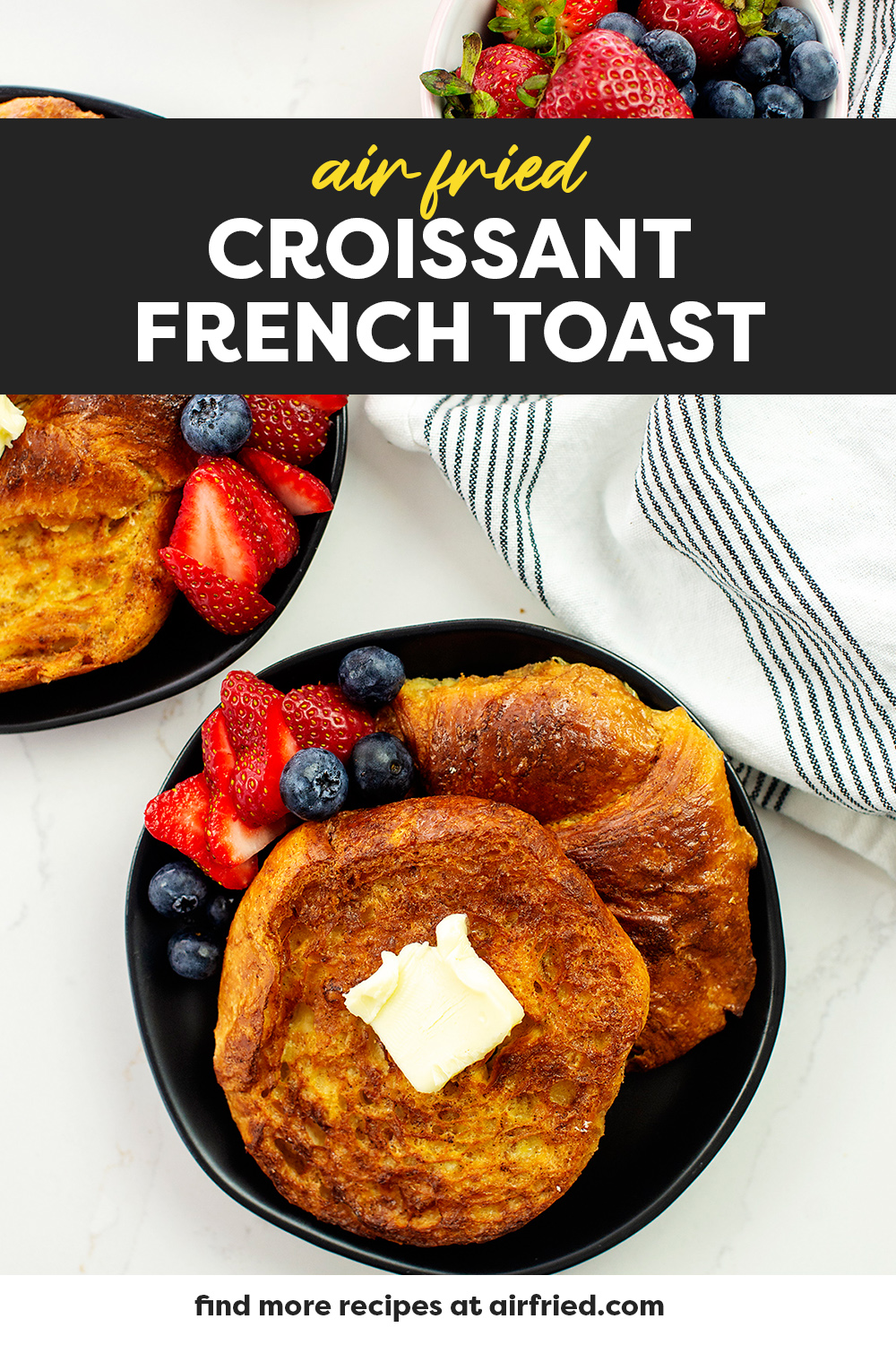 Croissant French toast and fruit on a black plate.