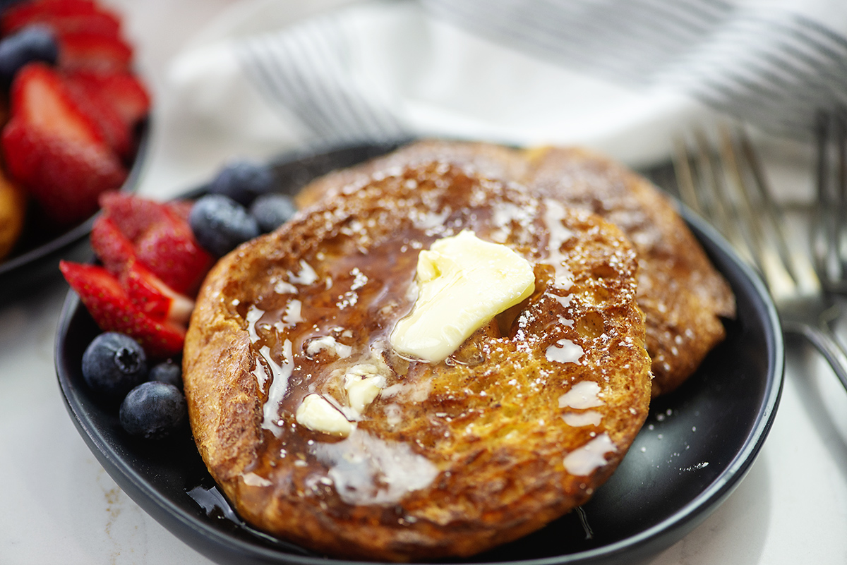 Croissant French toast on a black plate.