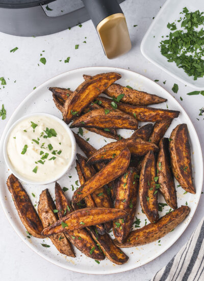 Sweet potato wedges in front of an air fryer.