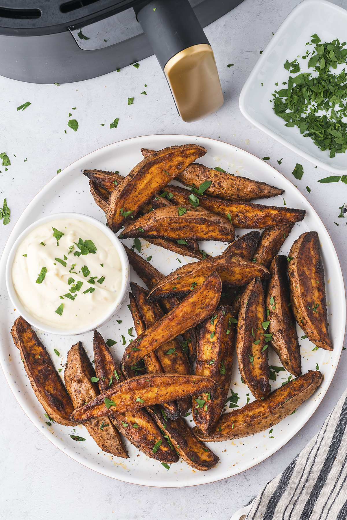 Sweet potato wedges in front of an air fryer.