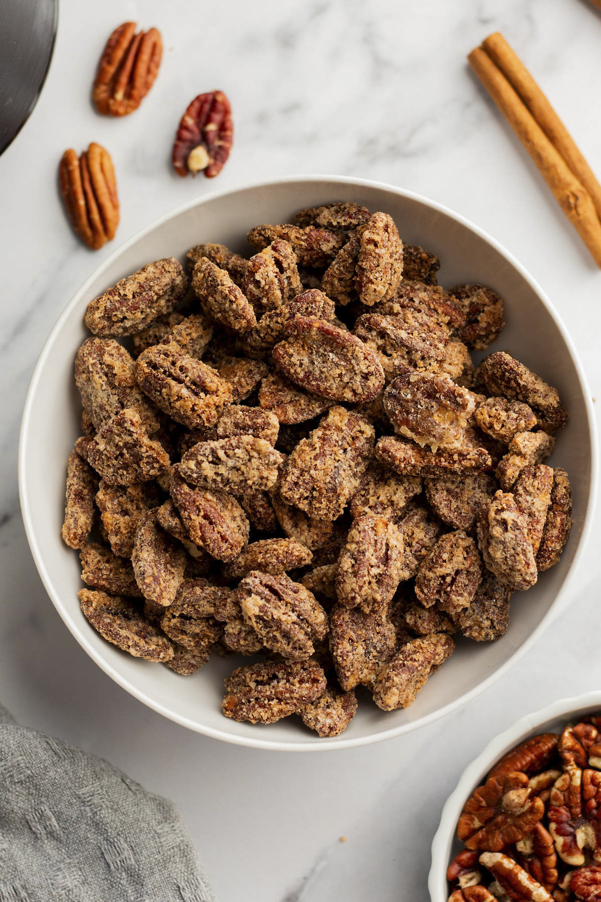 A white bowl full of candied pecans.