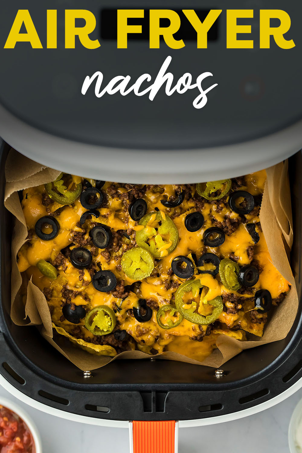 Air Fryer Nachos are made with seasoned ground beef, tortilla chips, and all the melty cheese and toppings to go with it! Enjoy these nachos while watching the big game or serve them up as a quick meal!