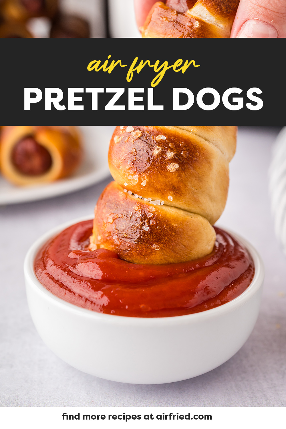 A pretzel dog being dipped into ketchup.