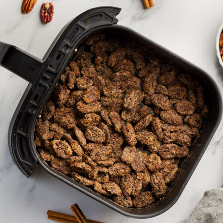 A bunch of candied pecans in an air fryer basket.