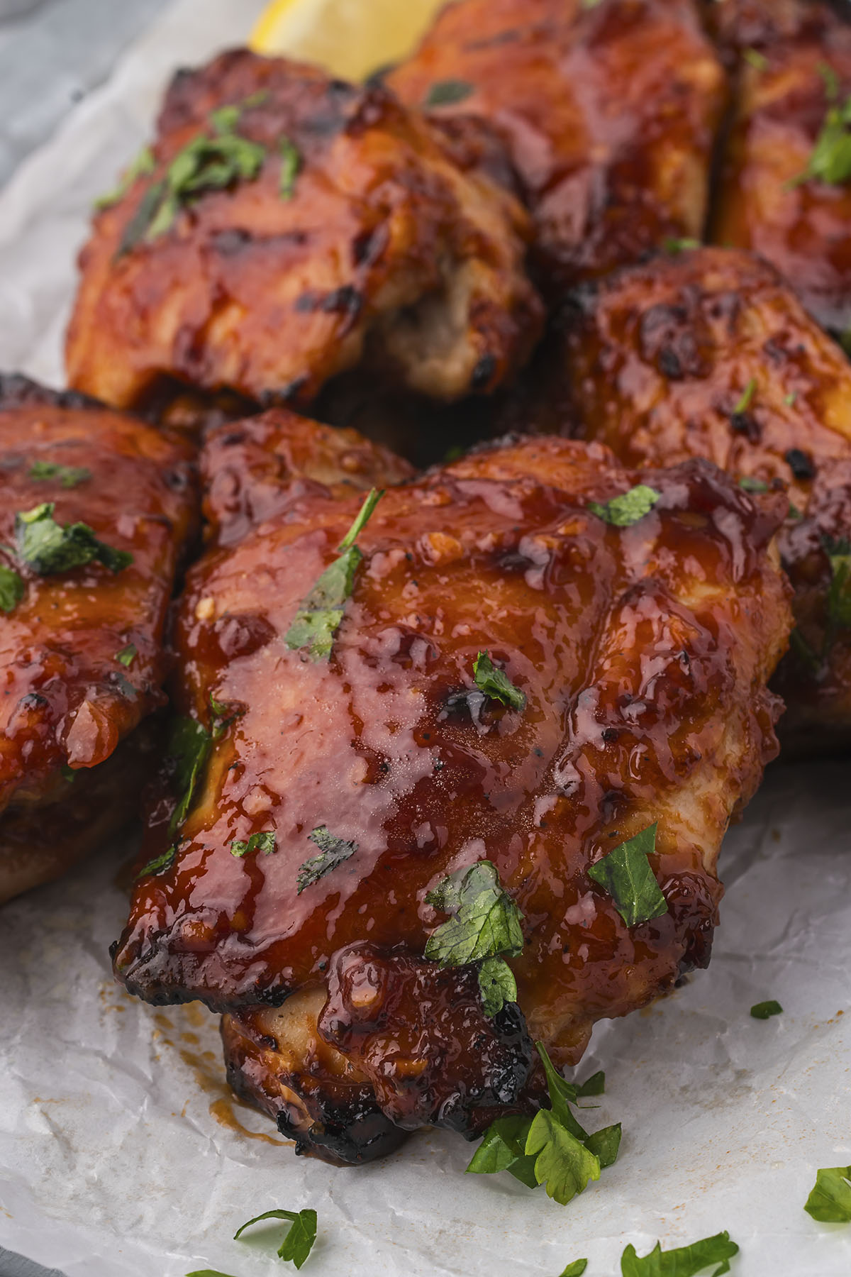 Close up picture of a BBQ chicken thigh in front of several other BBQ chicken thighs.