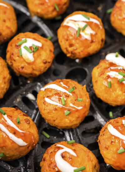 Close up of cooked Buffalo chicken meatballs in an air fryer basket.