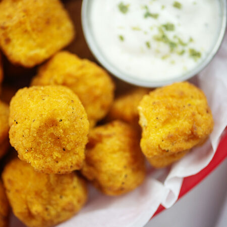 Popcorn chicken in red basket with ranch.