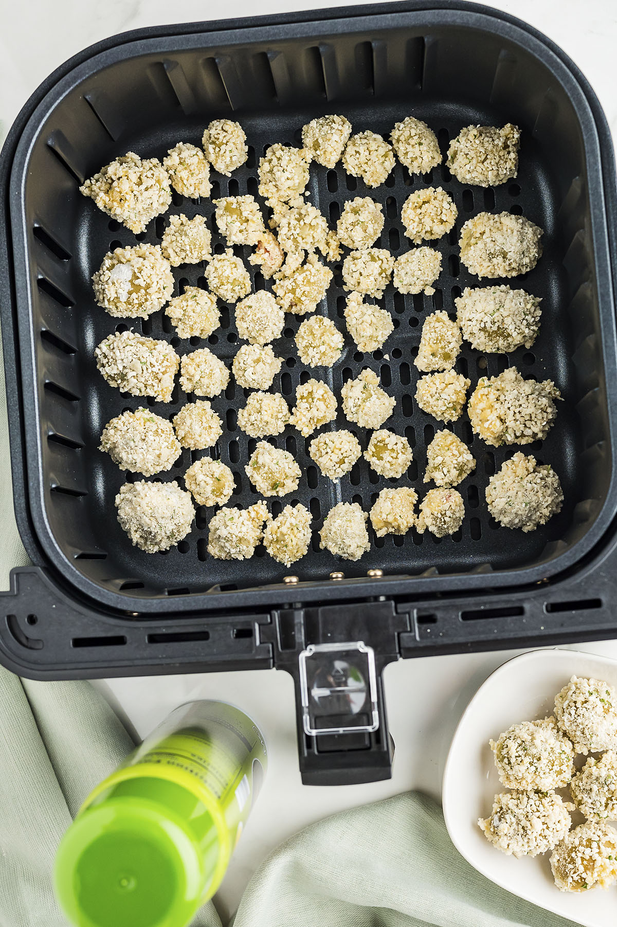 Uncooked fried olives in an air fryer basket.