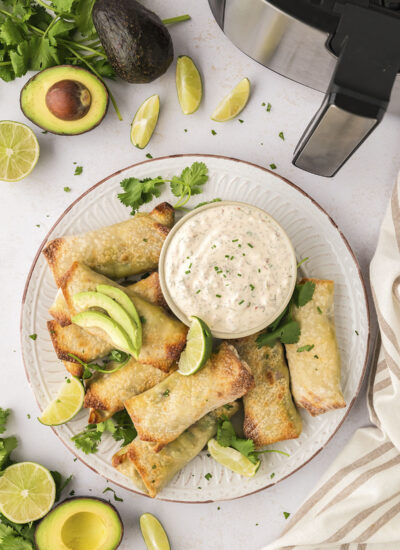 A white plate full of avocado egg rolls and homemade ranch dip.