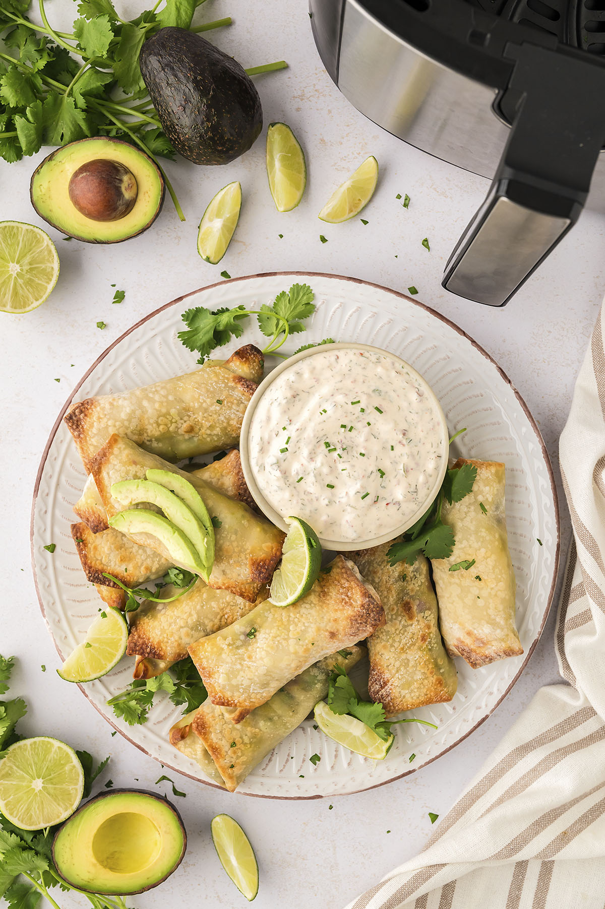 A white plate full of avocado egg rolls and homemade ranch dip.