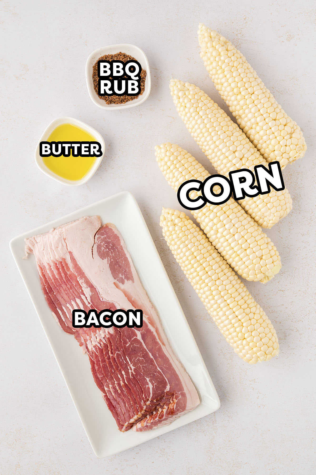 Ingredients needed for bacon wrapped corn on the cob on a white countertop.