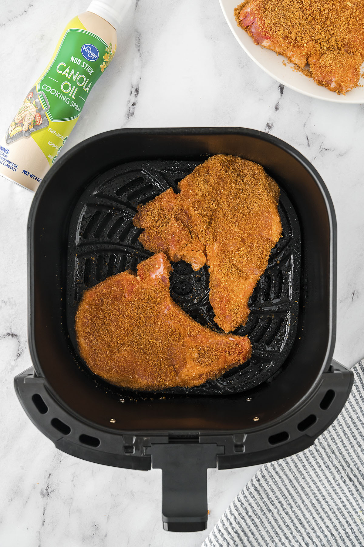 Breaded pork chops in air fryer basket.