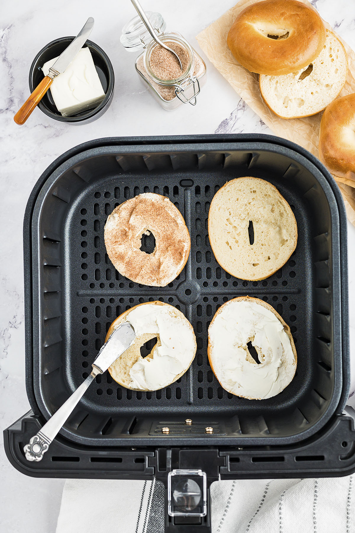 Bagels being spread with cream cheese.