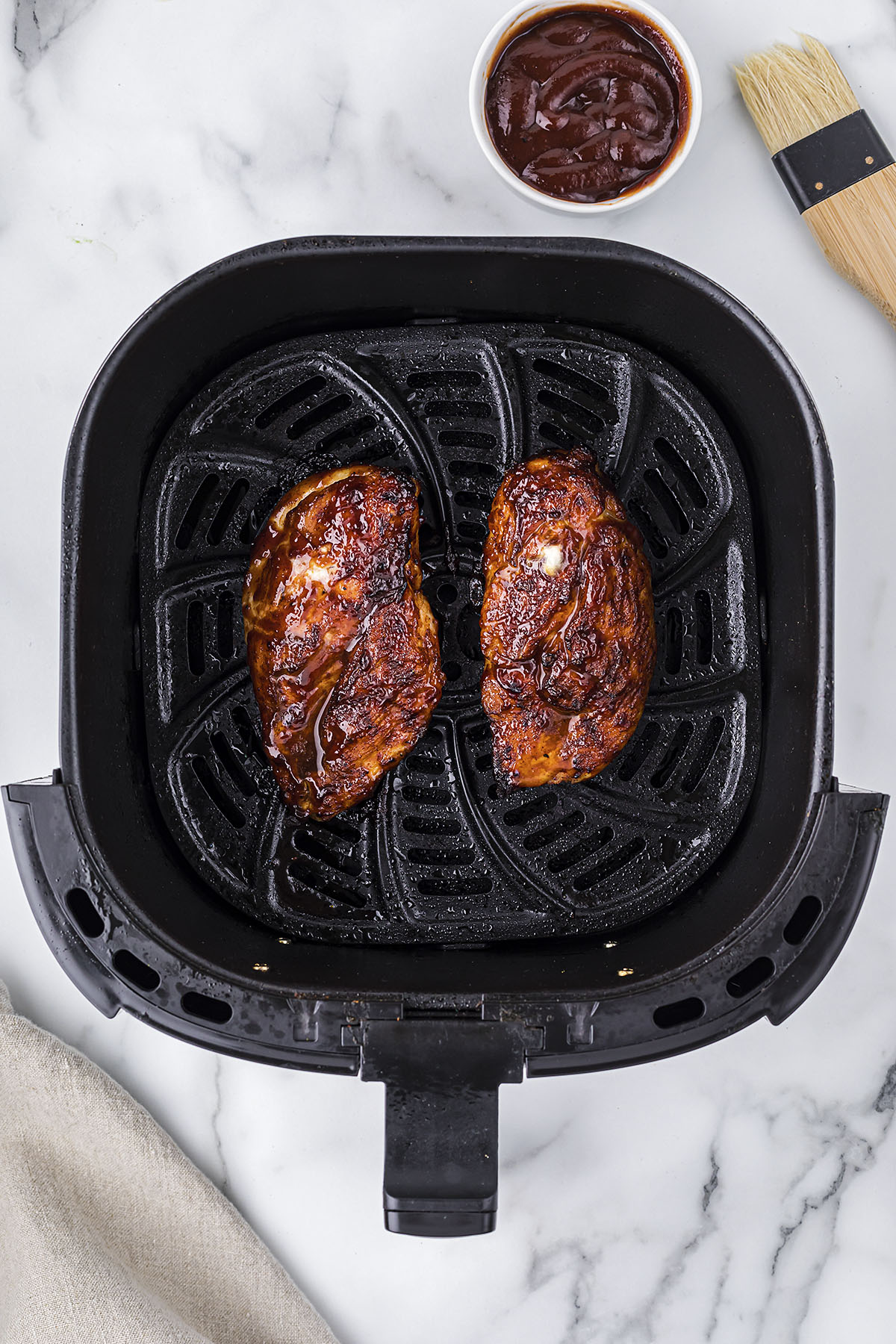 BBQ chicken breasts in air fryer basket.