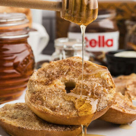 Churro bagel being drizzled with honey.