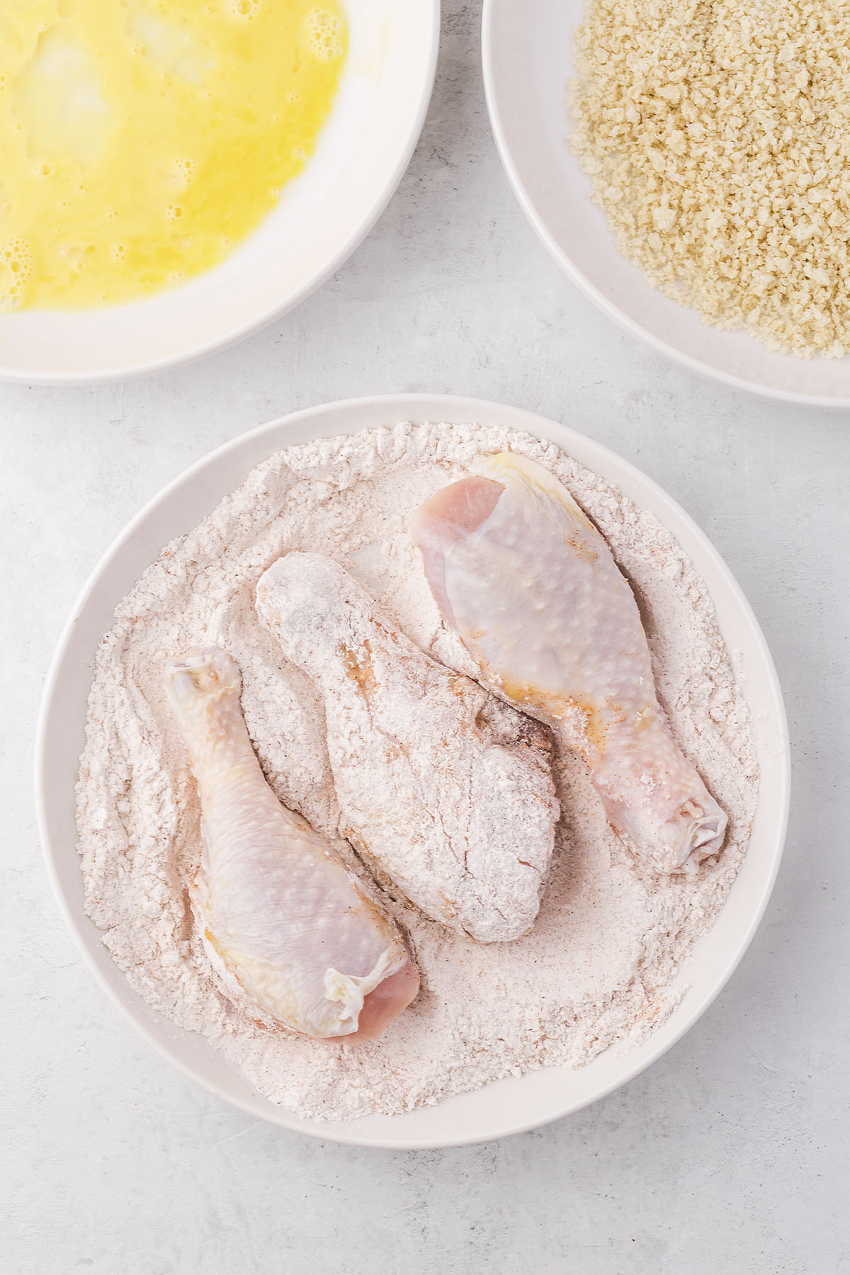 Chicken being dredged in flour.