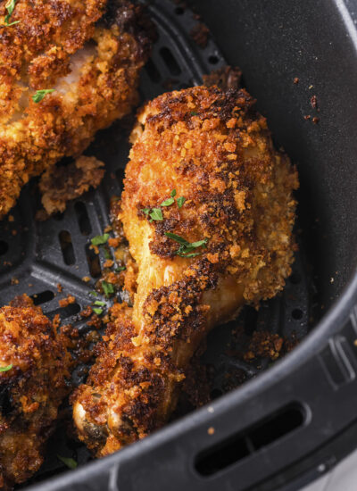 Crispy chicken legs in air fryer basket.