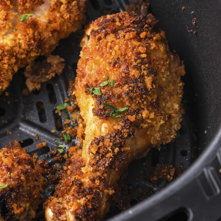 Crispy chicken legs in air fryer basket.