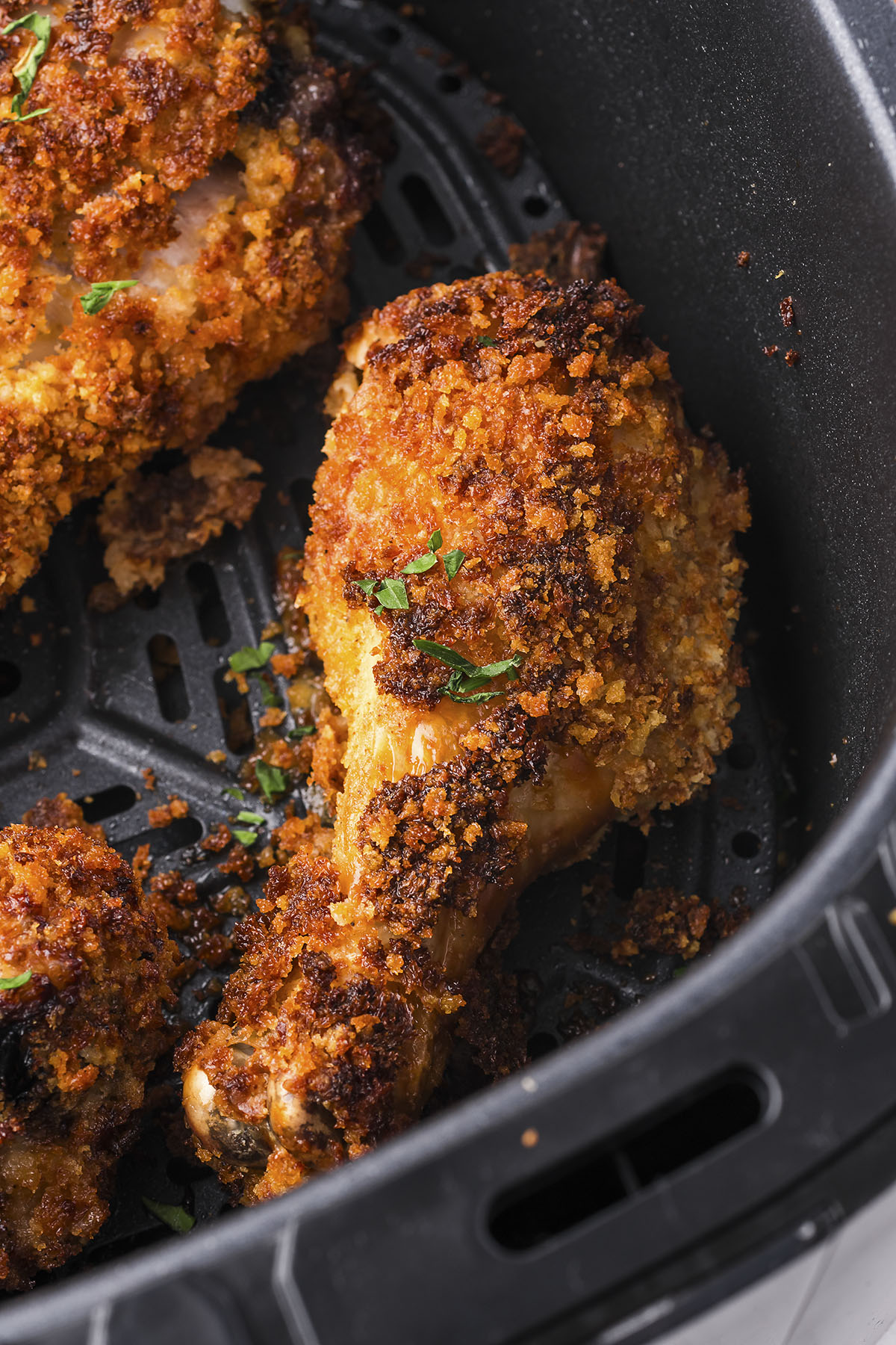 Crispy chicken legs in air fryer basket.