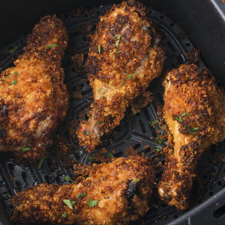 Crispy chicken legs in air fryer basket.