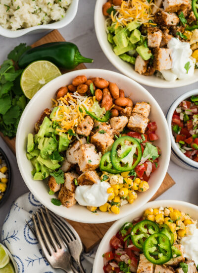 Several chicken burrito bowls on a table close together.