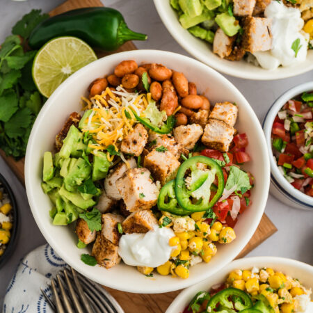 Several chicken burrito bowls on a table close together.