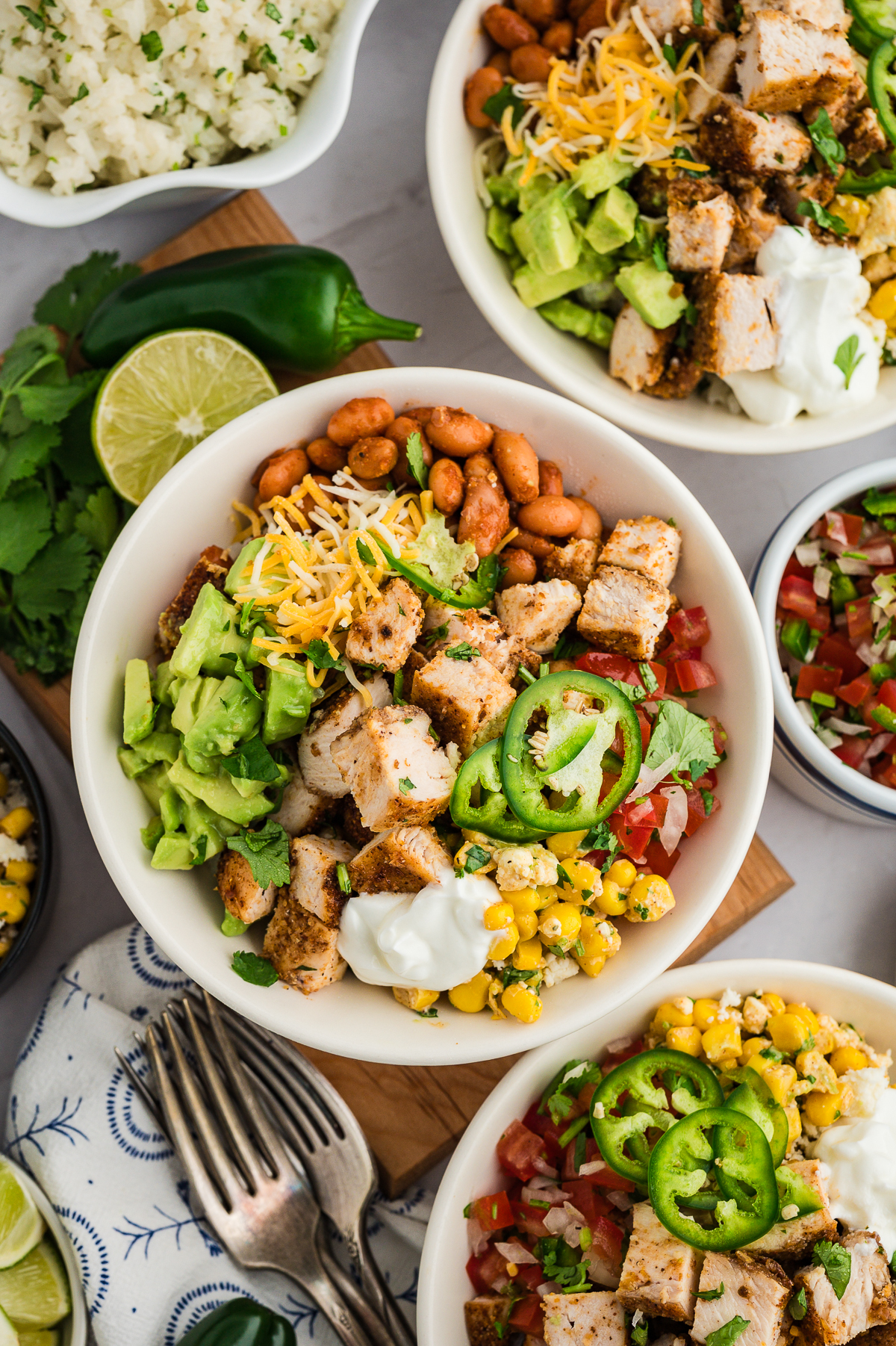 Several chicken burrito bowls on a table close together.