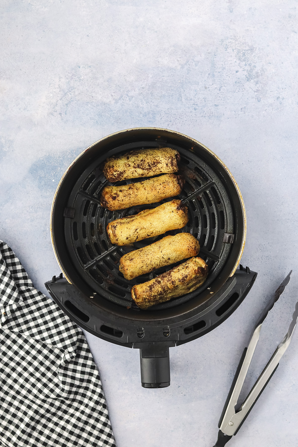 Cooked french toast roll ups in air fryer basket.