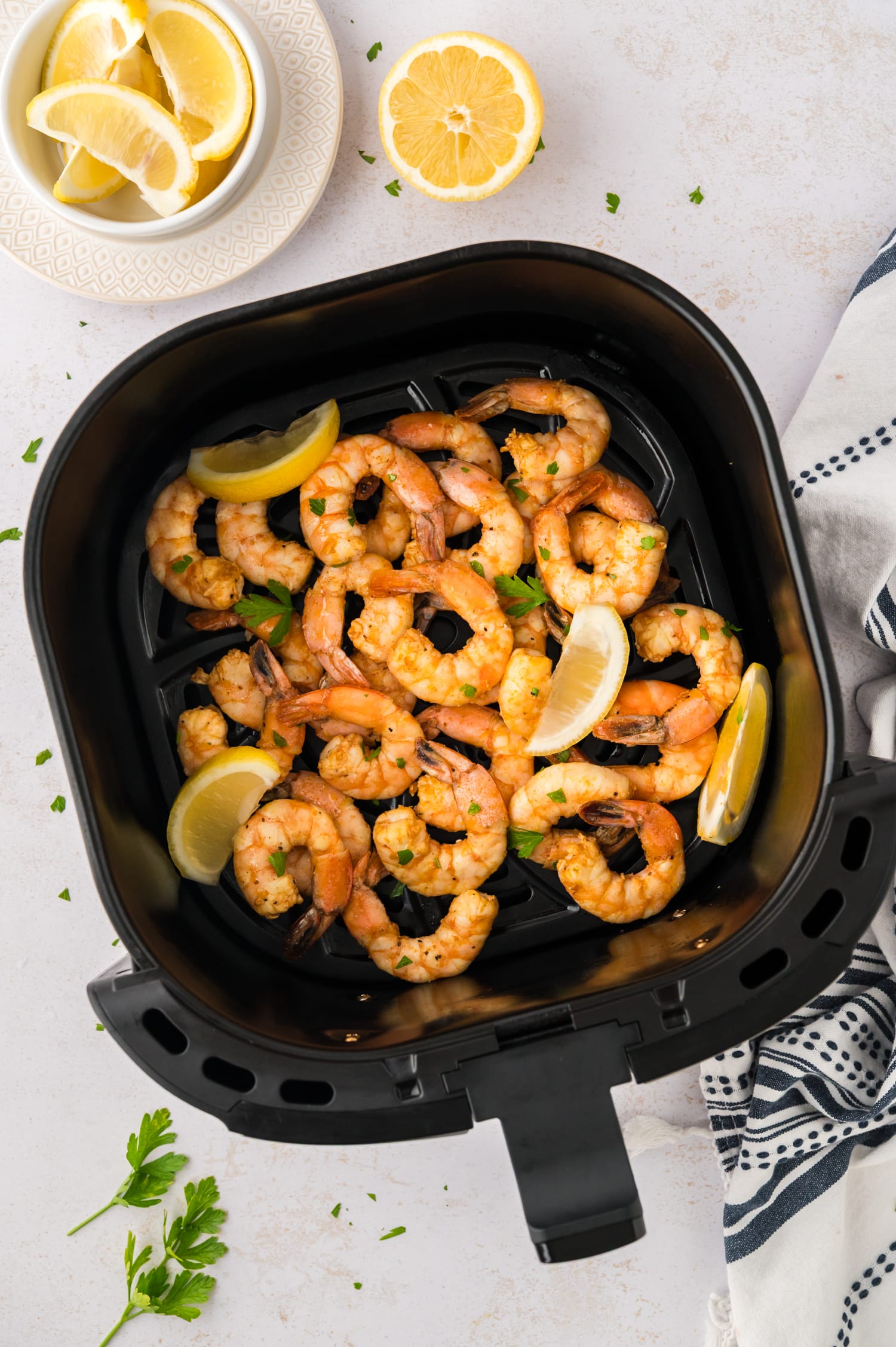 Air fryer basket full of lemon pepper shrimp.