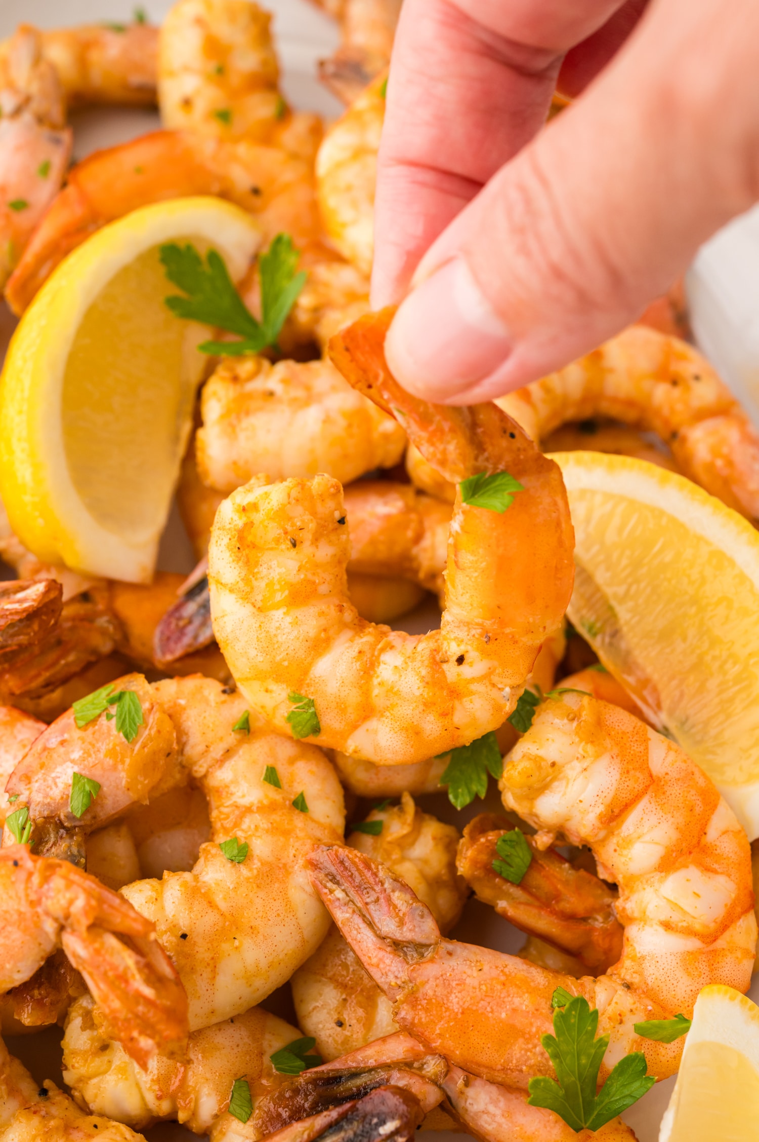 Close up of a hand pinching a piece of shrimp.