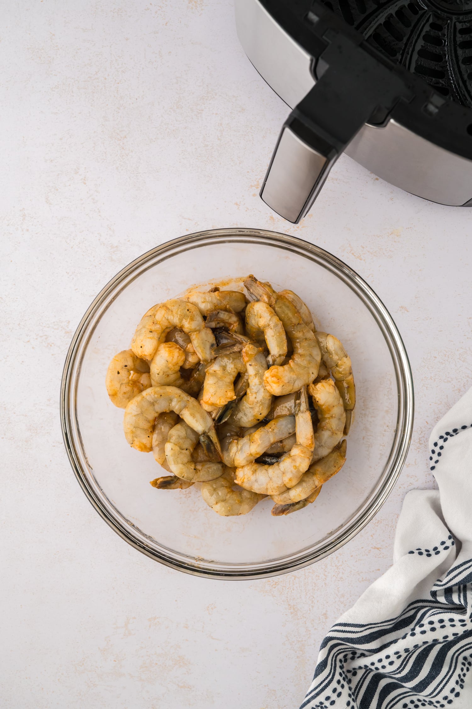 Seasoned raw shrimp in a glass bowl.