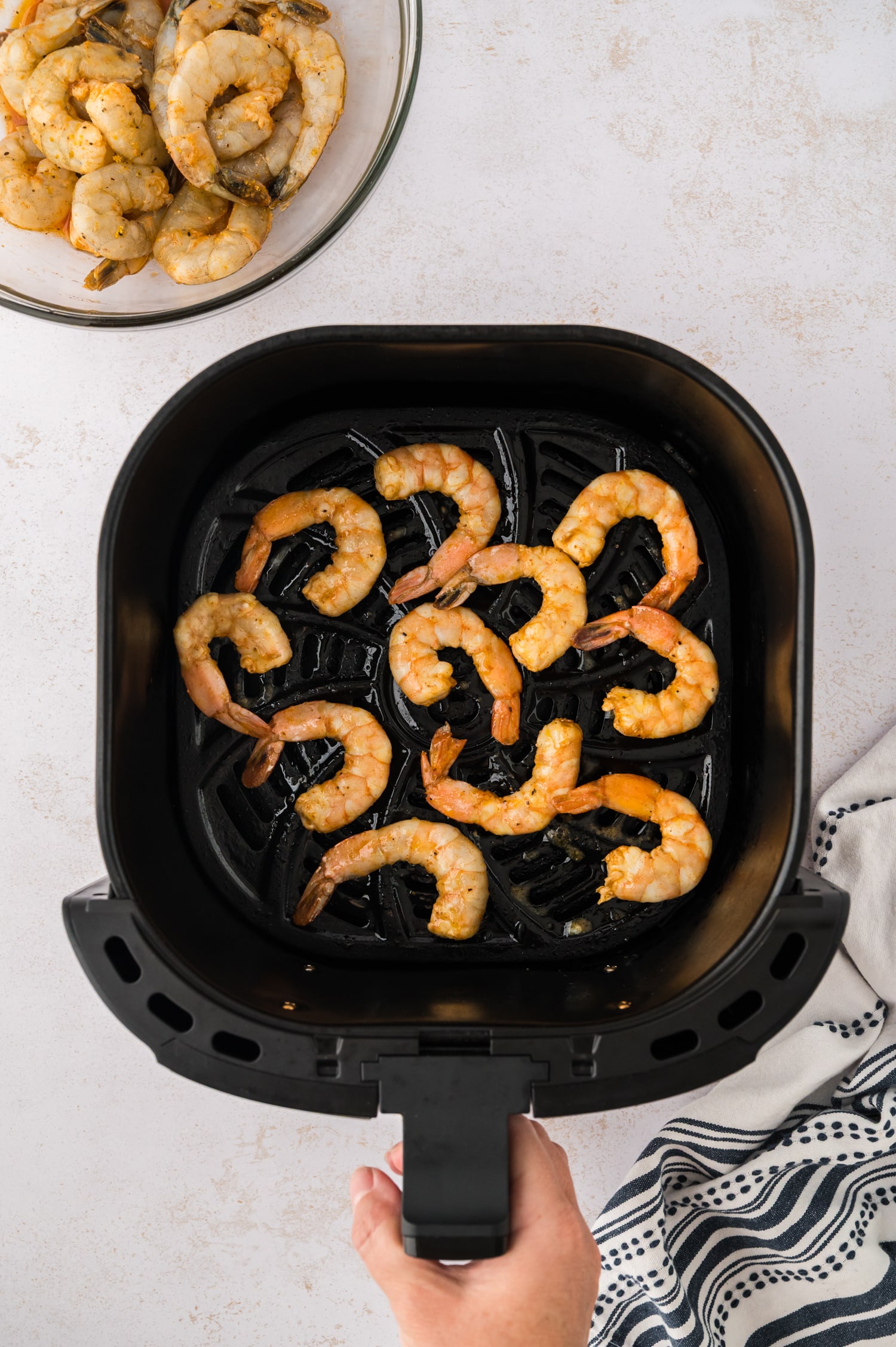 Several pieces of cooked shrimp in an air fryer basket.