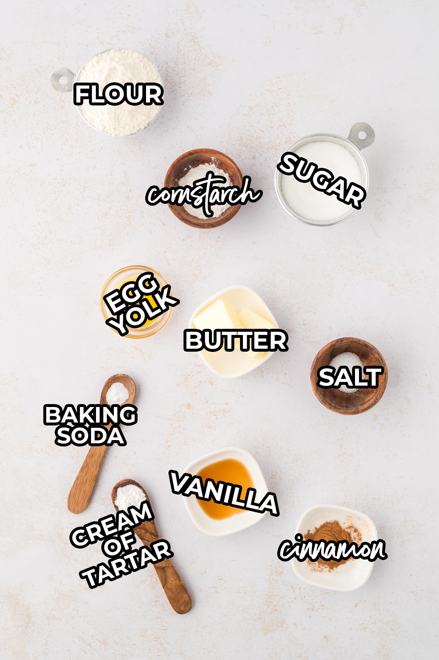 The ingredients for making two snickerdoodle cookies are arranged on a white countertop.