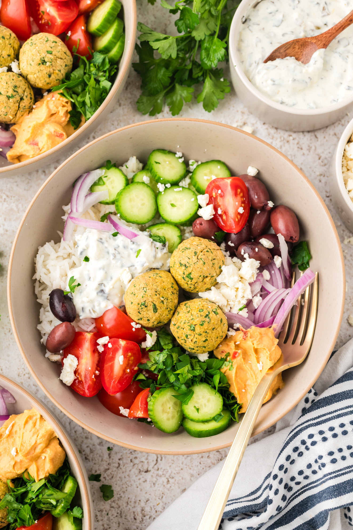 Bowl full of rice, falafel, and fresh veggies.
