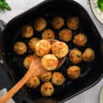 Overhead view of a wooden spoon with three chicken meatballs on it.