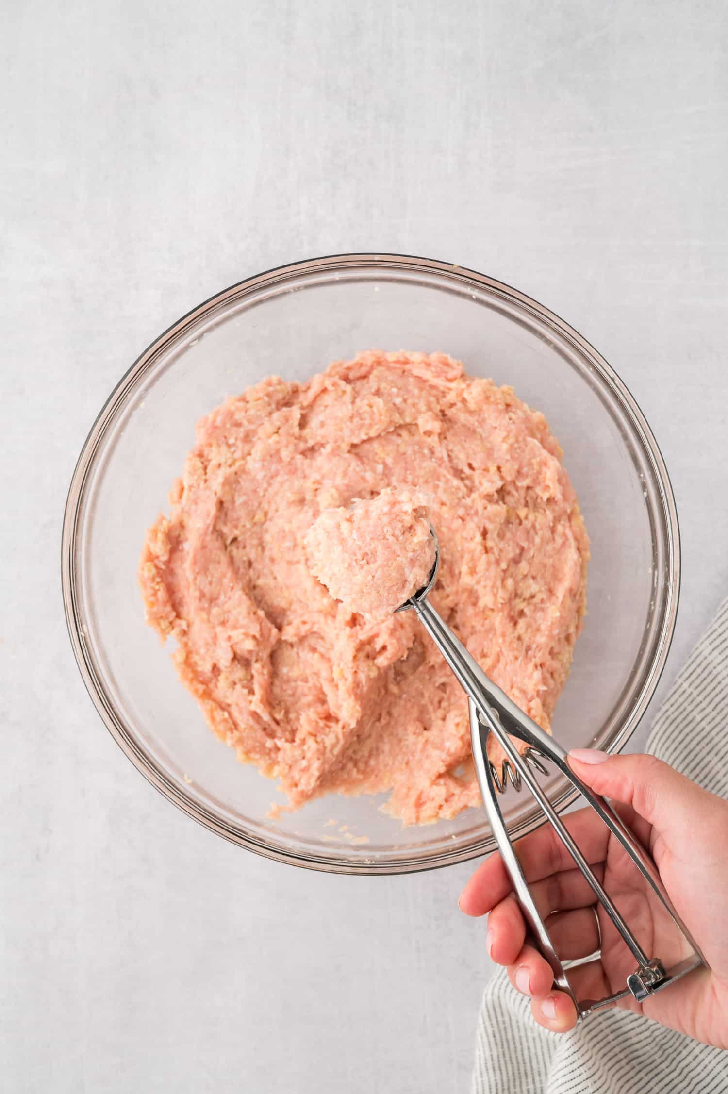 A large cookie scoop scooping a meatball mixture.