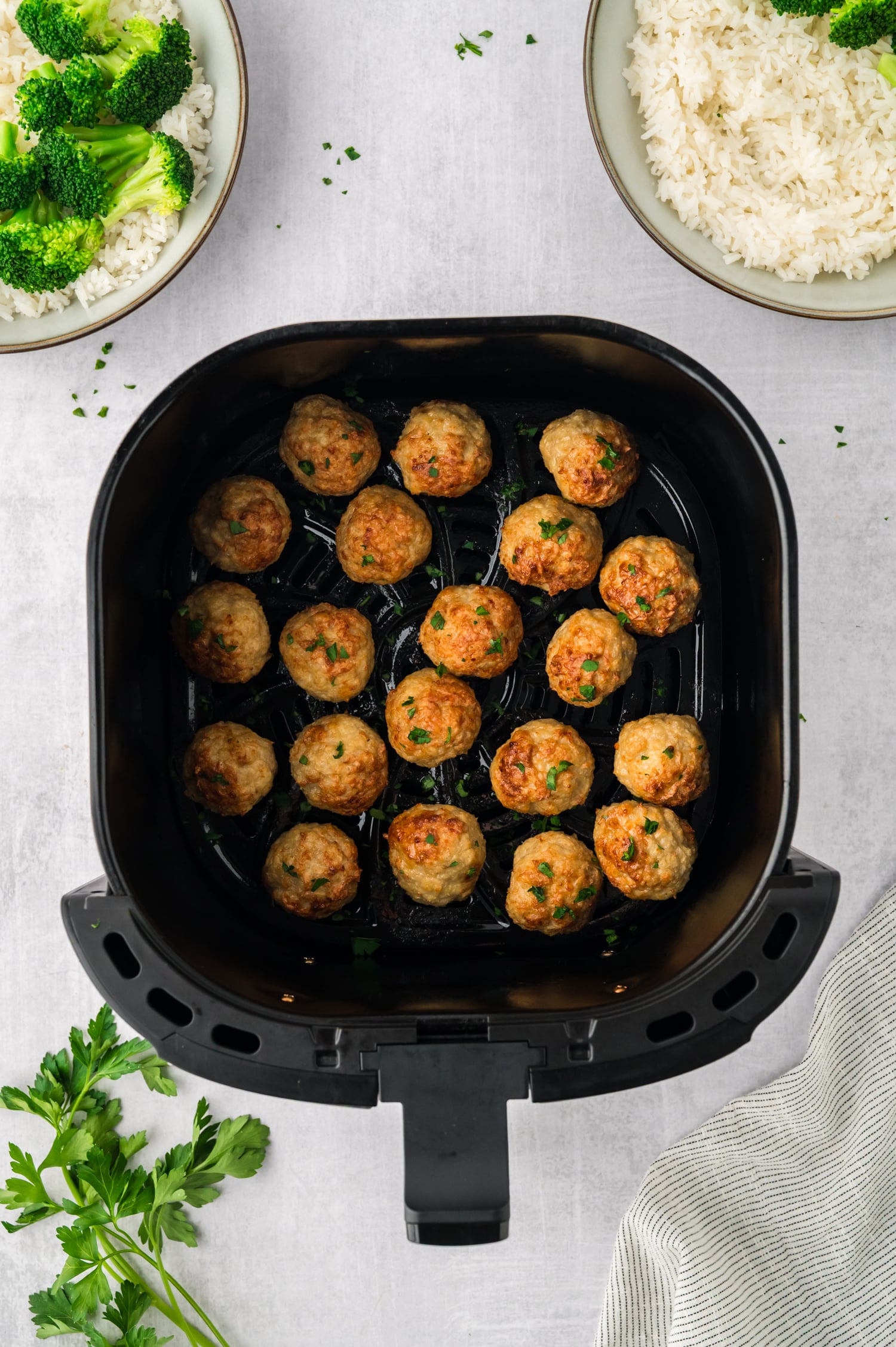 An air fryer basket full of cooked chicken meatballs.