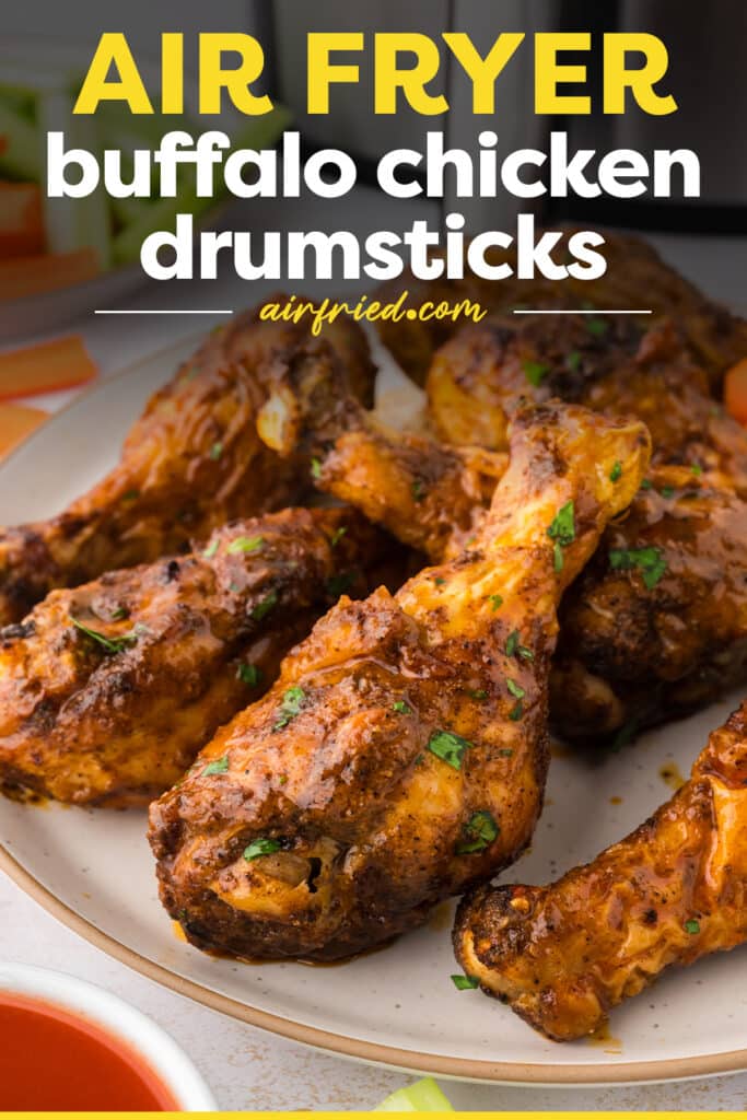 A close-up of buffalo drumsticks arranged on a white plate, their sauce-coated skin glossy and richly colored.