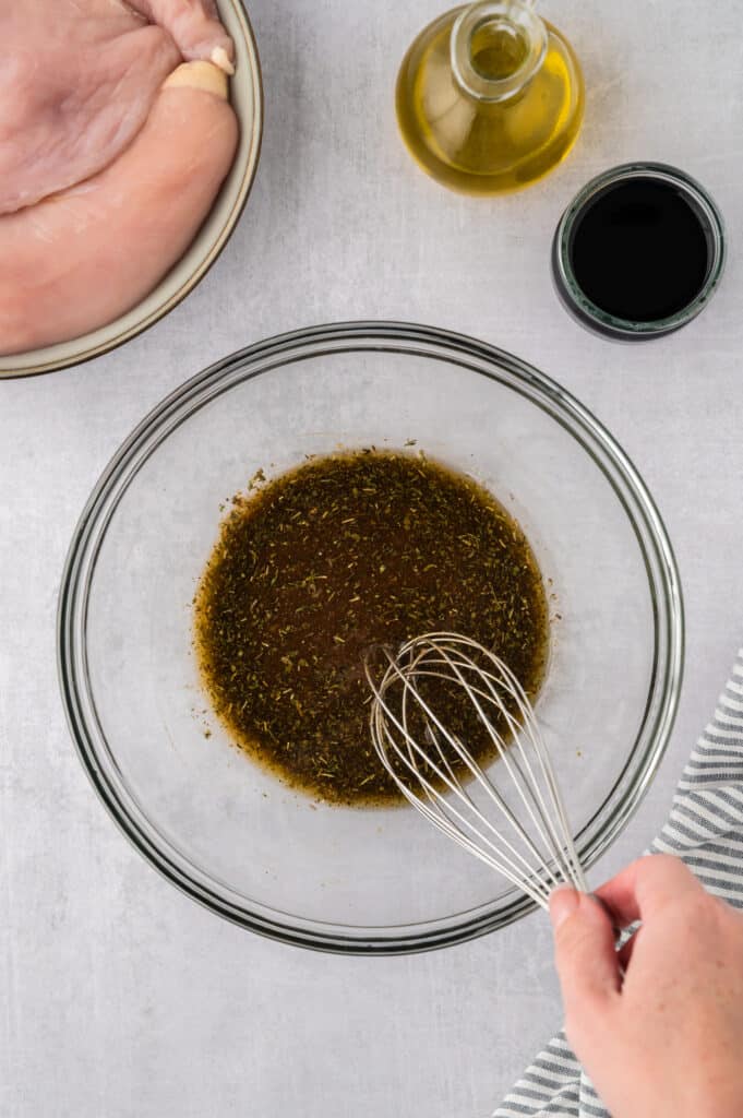 Balsamic seasoning is being mixed together in a clear glass bowl.