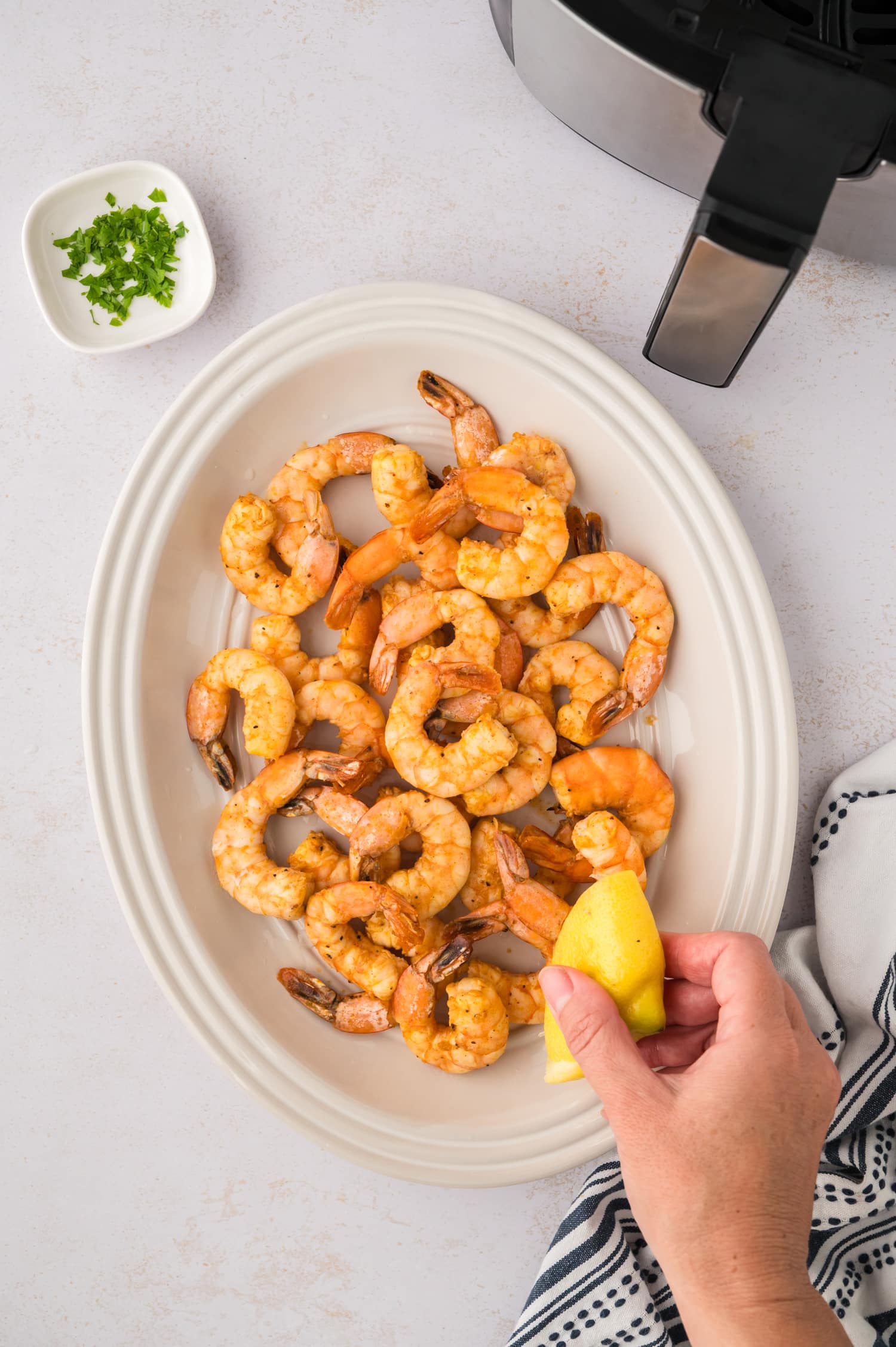 Lemon being squeezed over cooked shirmp.