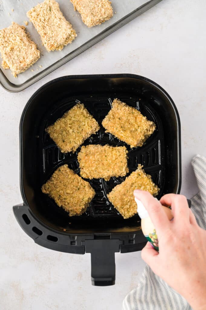 Uncooked mozzarella sticks are arranged in a single layer inside an air fryer basket.