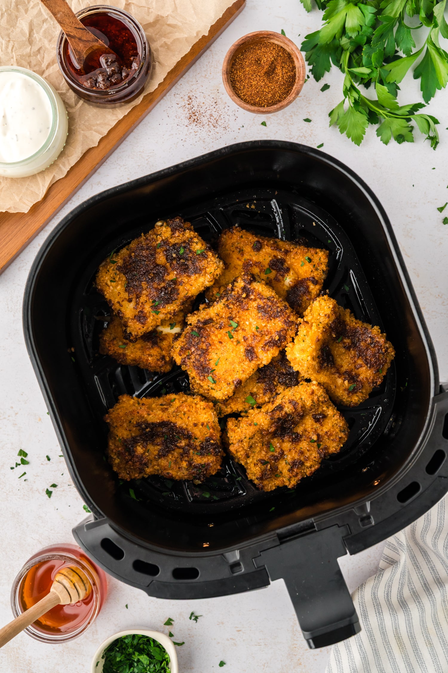 An overhead view of an air fryer basket filled with Nashville hot mozzarella sticks arranged in a single layer.