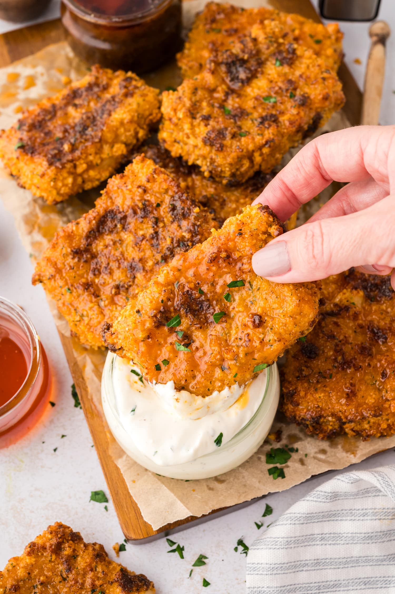 A woman’s hand holds a Nashville hot mozzarella stick as it is dipped into a cup of ranch dressing.