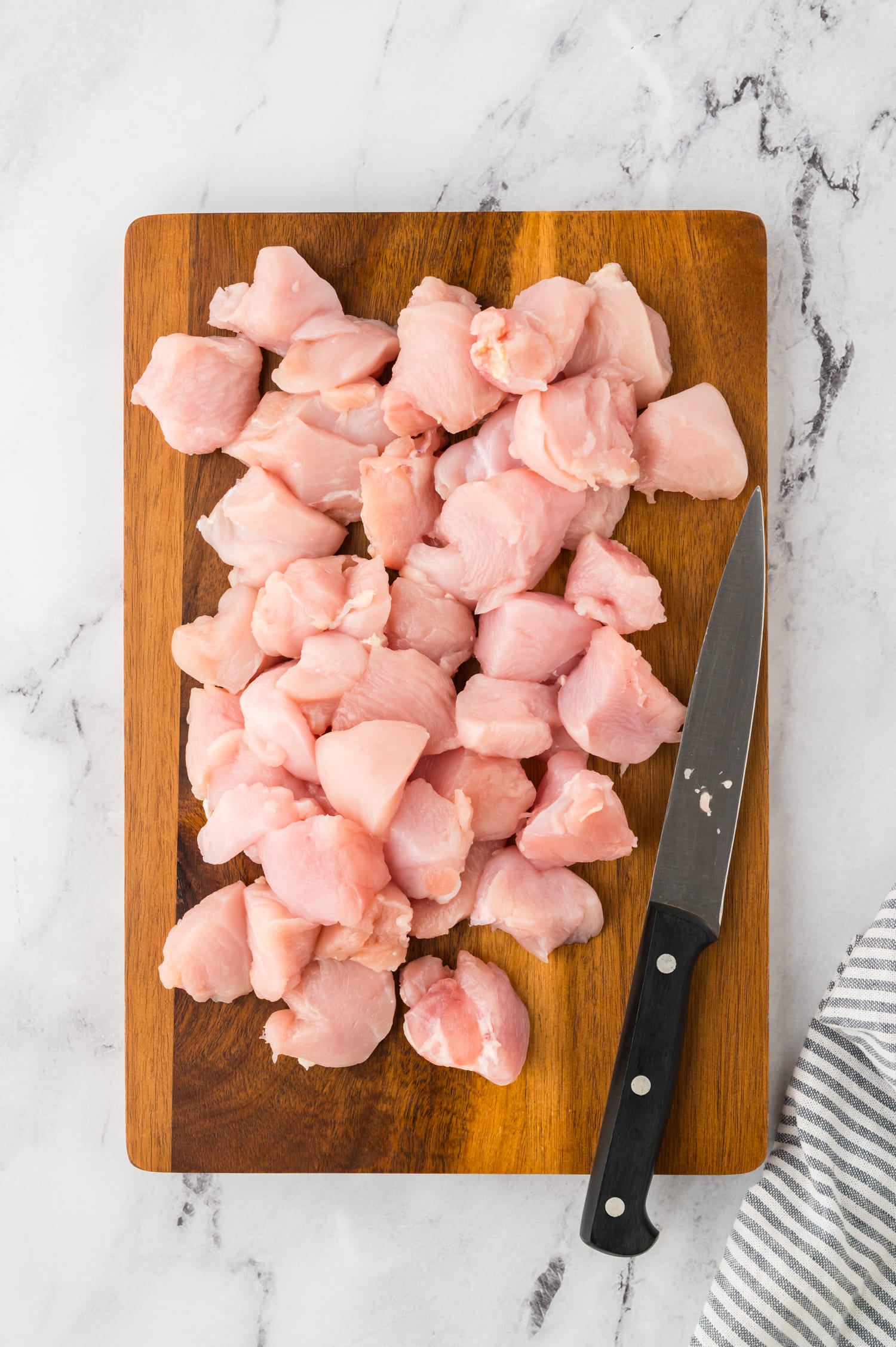 Raw chicken cut to pieces on a wooden cutting board.