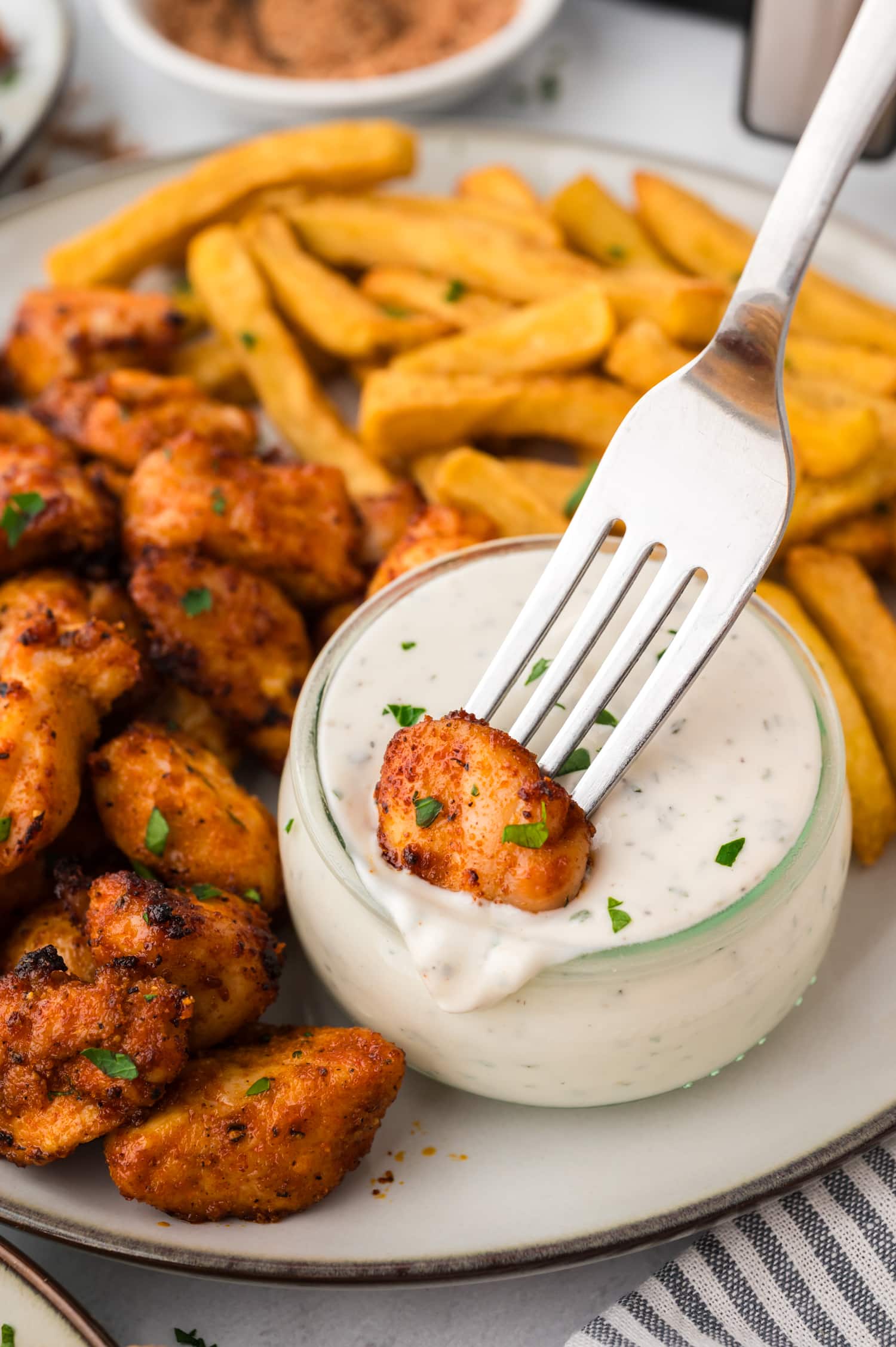 Close up of a fork dipping a chicken bite into ranch dressing.