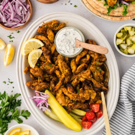 Overhead view of a plate full of chicken shawarma surrounded by toppings.