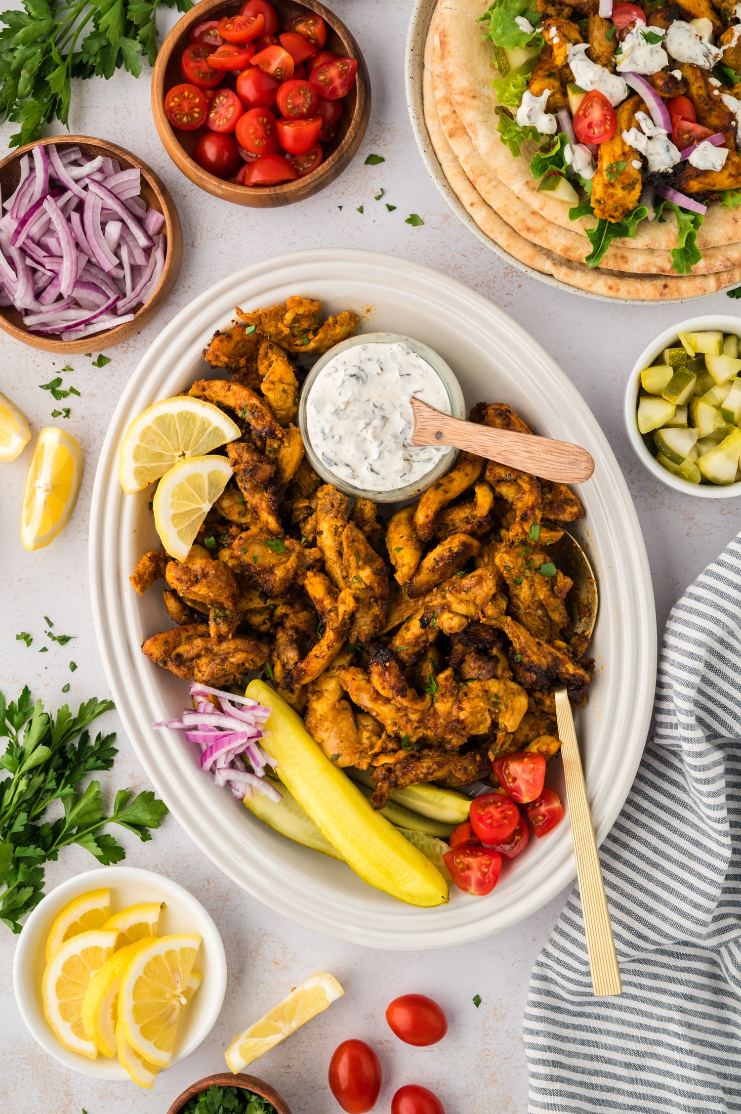 Overhead view of a plate full of chicken shawarma surrounded by toppings.
