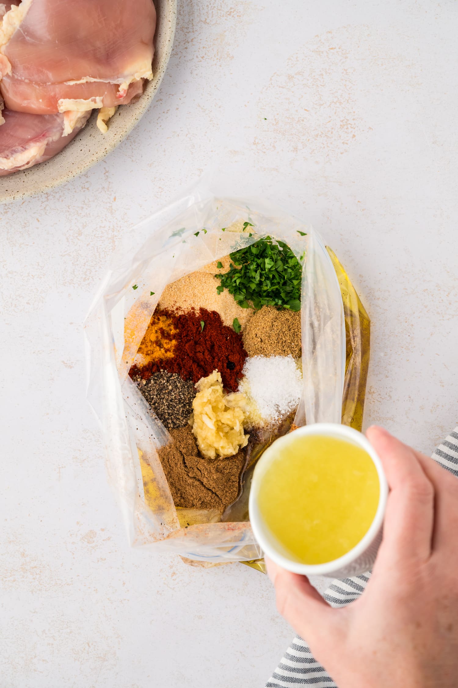 Various seasonings being poured into a freezer bag.